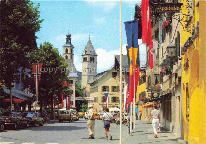 Kitzbuehel Tirol AT Vorderstadt Kirchturm Apotheke Geschaefte Passanten Flaggen