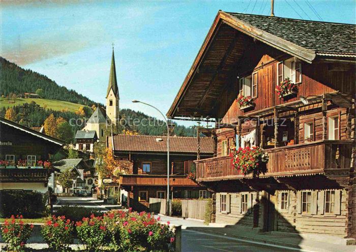Kirchberg Tirol AT Strassenpartie Kirchturm Bauernhaeuser Holzbalkon Blumen Somm