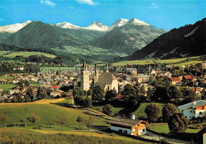 Kitzbuehel Tirol AT Pfarrkirche Kirchturm Alpengipfel Ortschaft Wiesen Baeume Be