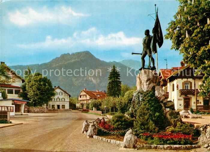 Kochel See Dorfstrasse mit Schmied von Kochel-Denkmal